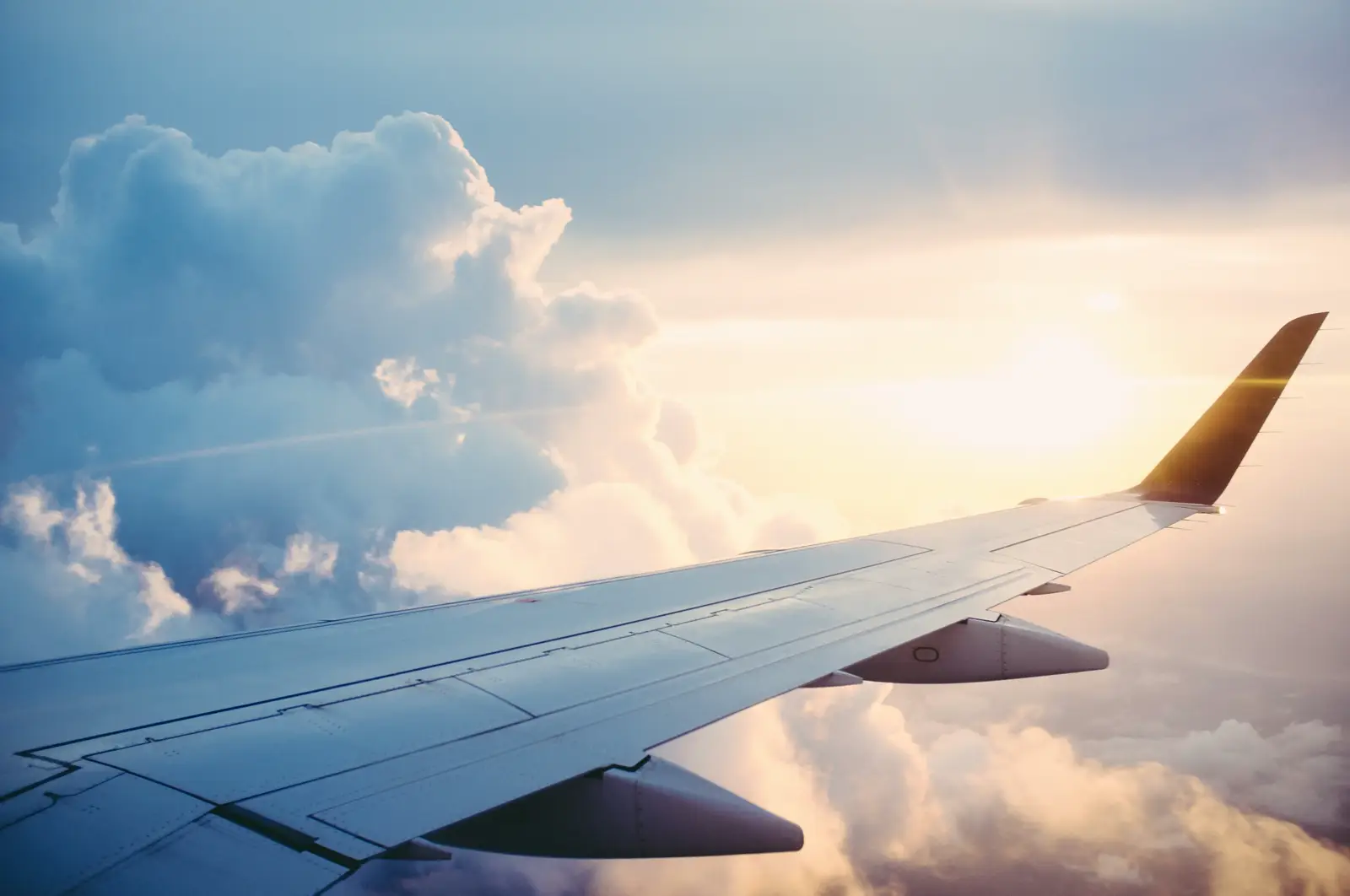Aircraft wing above the clouds at dawn